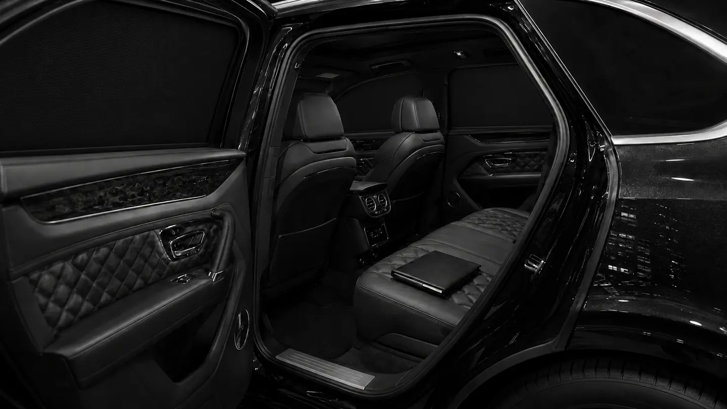 A private Bentayga rear cabin with its window blinds raised and a closed folio on the seat