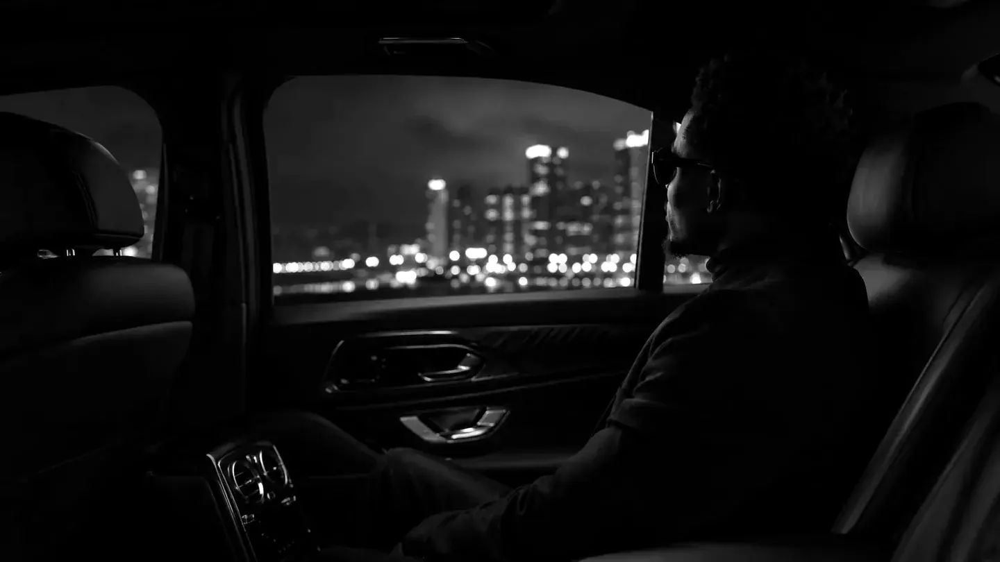 A passenger sitting quietly in a dark vehicle while light moves beyond the glass