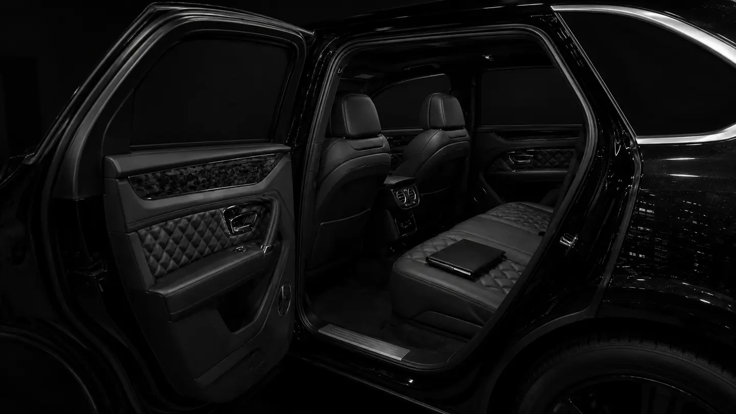 A private rear cabin at night with conventional front-hinged rear doors and a closed folio on the seat